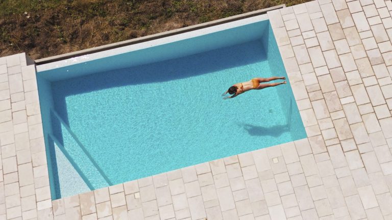 Woman swimming in a rectangular fiberglass pool - Pools By York
